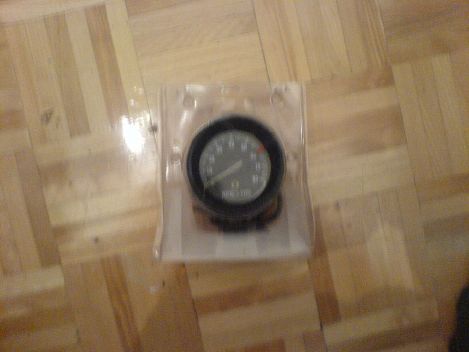 Tachometer gauge in plastic packaging on wood floor