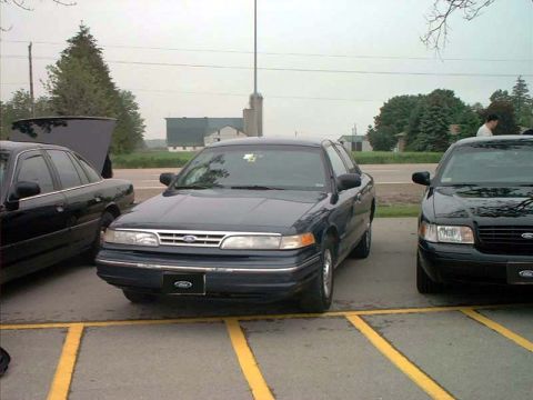 2000 Ford Crown Victoria - Two Ford Crown Victorias are parked side-by-side in a parking lot.