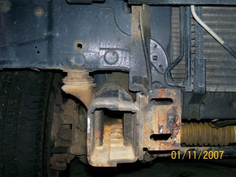 1996 Ford Bronco - Close-up view of the front bumper bracket and radiator assembly, showing rust and wear.