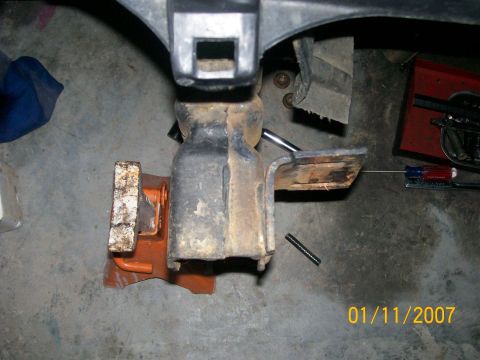 1996 Ford Bronco - A vehicle suspension component is secured by a jack stand on a concrete floor, with tools nearby.