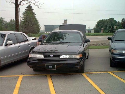 2000 Ford Crown Victoria - A black Ford Crown Victoria is parked in a lot with two other vehicles visible.