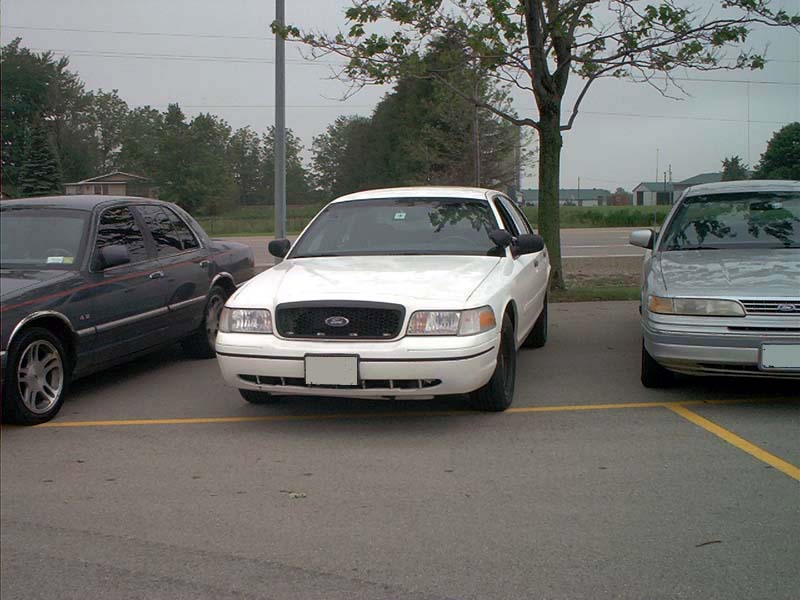 White 2000 Ford Crown Victoria front view parked between two other cars
