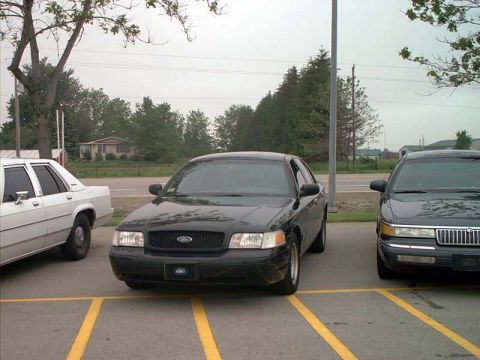 2000 Ford Crown Victoria - A black 2000 Ford Crown Victoria is parked in a lot with two other vehicles.