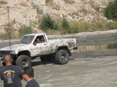 1987 Ford Bronco - White pickup truck navigating a muddy off-road course.