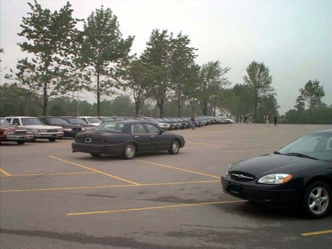 2000 Ford Crown Victoria - A dark sedan is parked in a lot with other vehicles visible in the background.