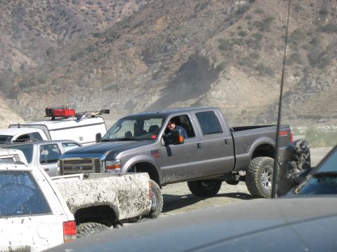 1987 Ford Bronco - A gray Ford F-250 Super Duty pickup truck is seen in a dusty, off-road environment with other vehicles.