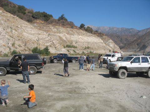 1987 Ford Bronco - Group of off-road vehicles and people gathered in a mountainous, dry riverbed area.
