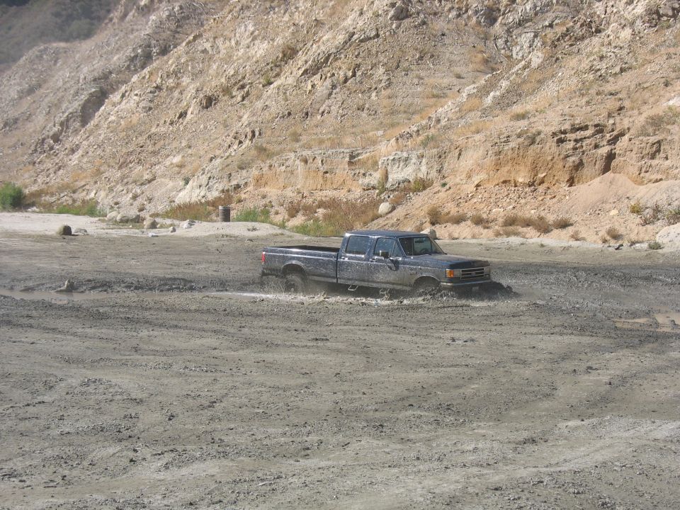 Ford F-Series truck driving through mud