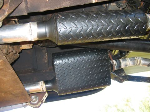 1992 Ford Mustang - The underside of a vehicle shows two exhaust pipes covered in black diamond plate material.