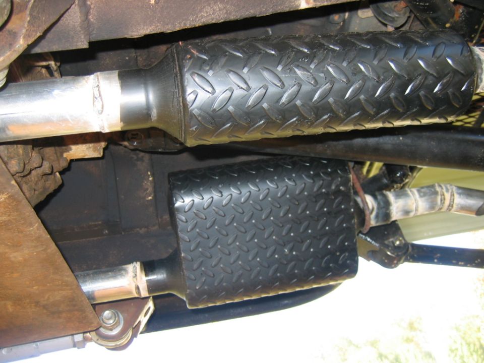 close-up of two exhaust pipes with black diamond plate covers