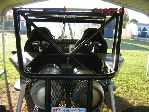 1992 Ford Mustang - The interior of a custom-built off-road vehicle, a roll cage and dual tanks, is viewed from the rear.