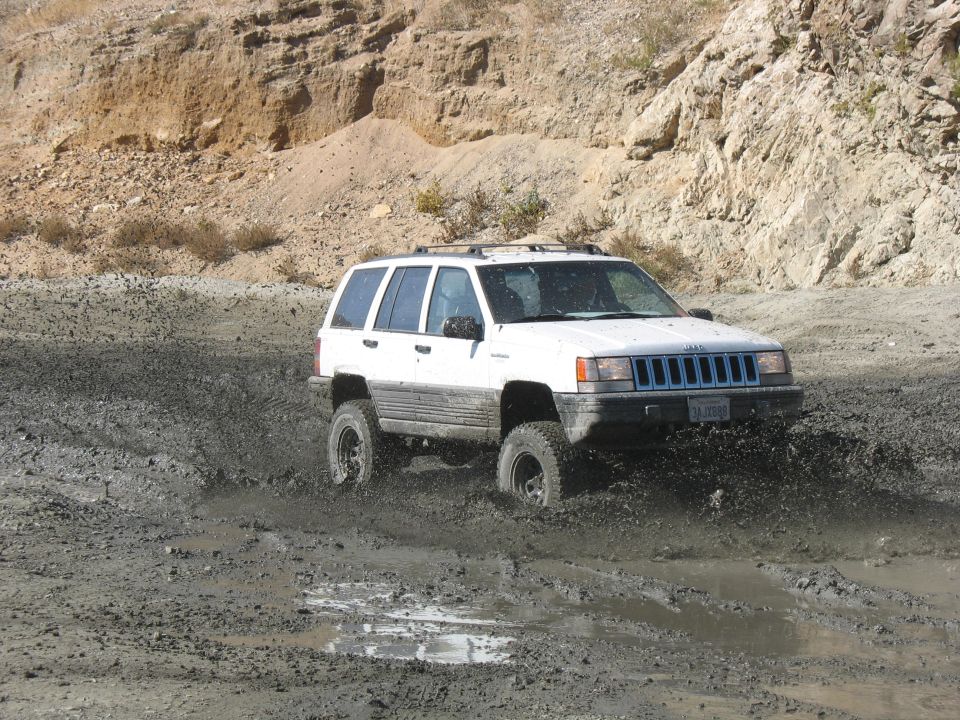 White Jeep Grand Cherokee splashing mud off-road
