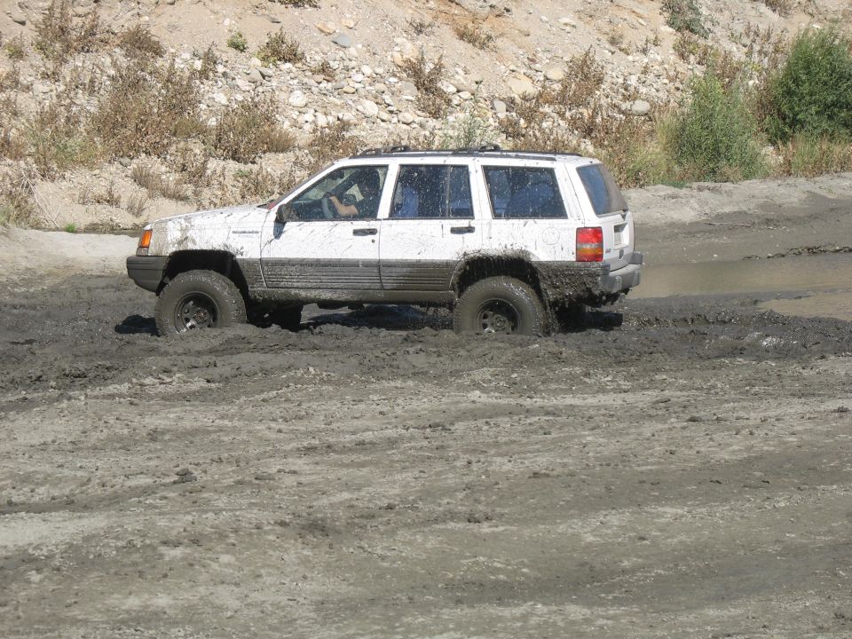 White Jeep Grand Cherokee stuck in mud, front wheels deep