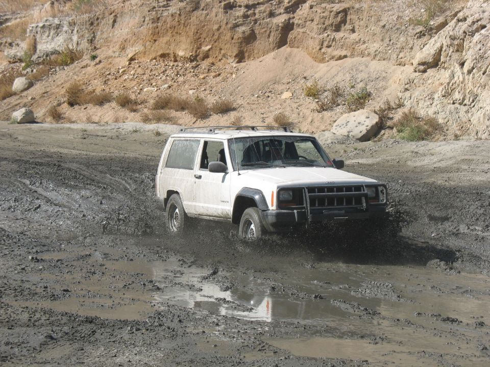 White Jeep Cherokee XJ driving through mud