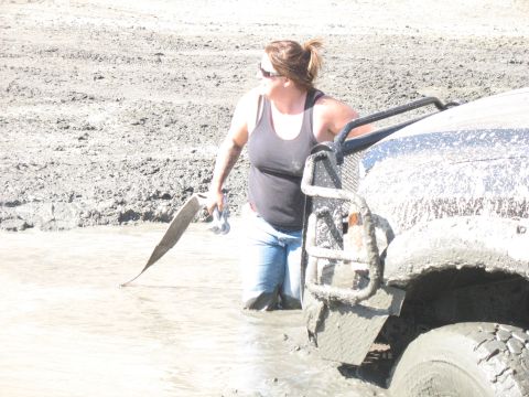 1987 Ford Bronco - A woman attempts to free a mud-covered vehicle stuck in a muddy mire.