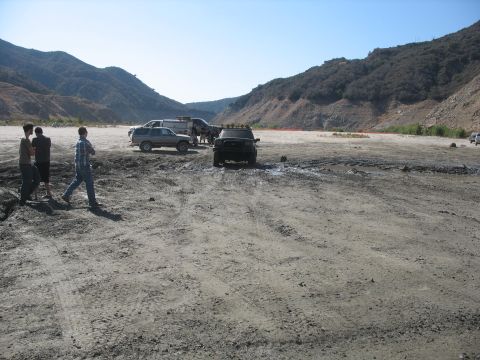 1987 Ford Bronco - Several off-road vehicles are gathered in a dusty, mountainous landscape.