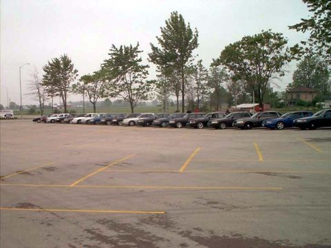 2000 Ford Crown Victoria - A row of police cruisers are parked in an outdoor lot under a cloudy sky.