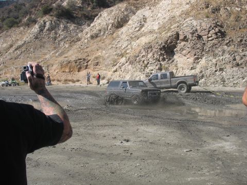1987 Ford Bronco - 1987 Ford Bronco navigating a muddy off-road course with a pickup truck nearby.