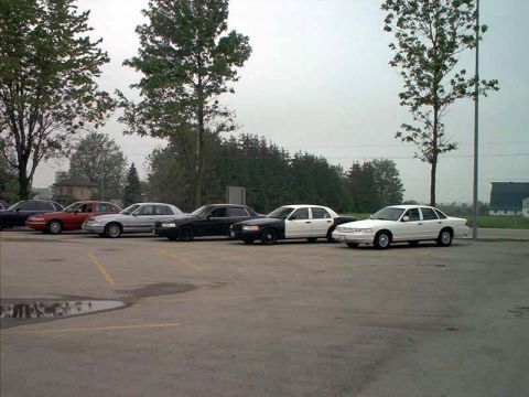 2000 Ford Crown Victoria - Multiple Ford Crown Victoria police cars are parked in a lot on an overcast day.