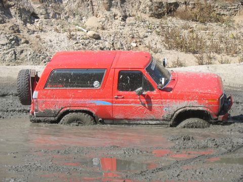 1987 Ford Bronco - This red 1987 Ford Bronco is deeply stuck in a muddy off-road area.