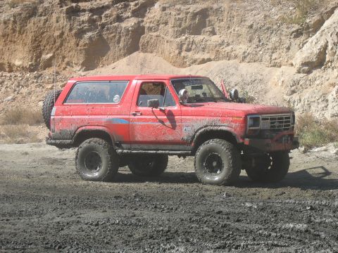 1987 Ford Bronco - Muddy 1987 Ford Bronco navigating rough terrain.