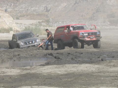 1987 Ford Bronco - A red SUV is stuck in the mud while another vehicle is also bogged down nearby.