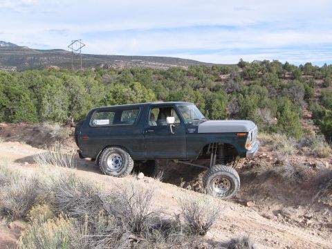 1979 Ford Bronco - This modified Ford Bronco is navigating a challenging off-road trail with steep inclines.