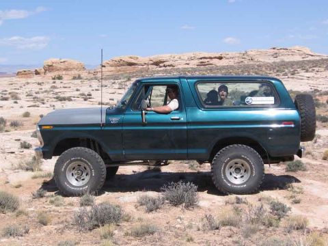 1979 Ford Bronco - A classic Ford Bronco navigates a rocky desert terrain under a clear blue sky.