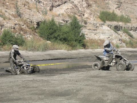 1987 Ford Bronco - Two ATVs are covered in mud as one attempts to pull the other out of a muddy ditch.