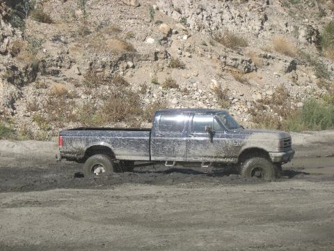 1987 Ford Bronco - This 1987 Ford F-Series pickup truck is stuck deep in the mud, with only its side profile visible.