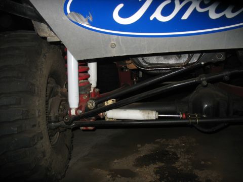 1987 Ford Bronco - Close-up of the front suspension and steering system on a 1987 Ford Bronco, showing the large tire and shock absorbers.