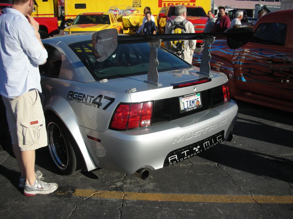 Silver Ford Mustang race car rear with tall wing and Agent 47 graphics at car show