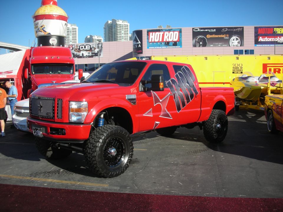 Lifted red Ford Super Duty crew cab pickup with star graphics at indoor show
