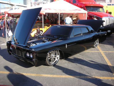 1998 Ford Crown Victoria - lowered black Lincoln Continental custom with hood raised and polished chrome wheels parked under show tents.