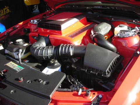 1998 Ford Crown Victoria - open engine bay of a red car shows a black corrugated air intake tube and an orange-topped engine cover.