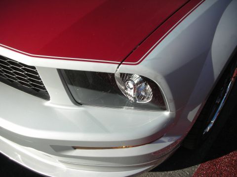 1998 Ford Crown Victoria - close-up of the front corner of a silver car with a red hood, showing the clear headlight assembly.