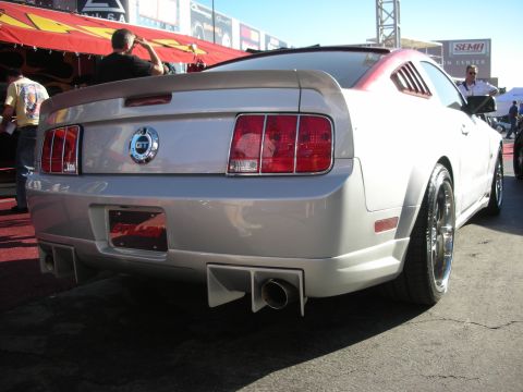1998 Ford Crown Victoria - rear of a silver Ford Mustang GT with custom diffuser and exhaust is shown outdoors at the SEMA show.