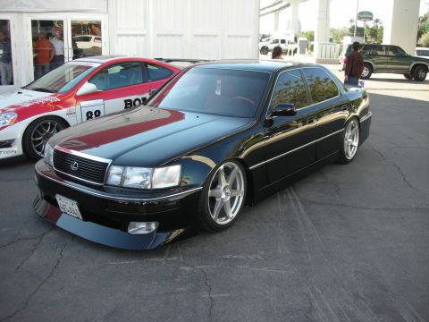 1998 Ford Crown Victoria - black lowered Lexus LS sedan with red roof trim and silver wheels sits parked on pavement at an event.