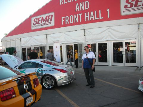 1998 Ford Crown Victoria - People gather outside a red SEMA Show registration tent marked Front Hall 1, with show cars parked in front.