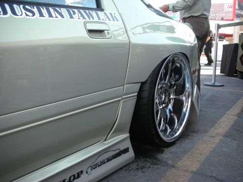 1998 Ford Crown Victoria - close-up of the rear quarter of a tan car shows a polished chrome wheel and a Justin Pawlak window decal.