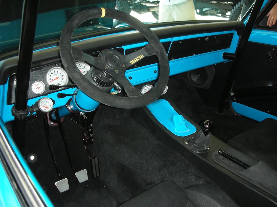 Interior of a race-prepped car with suede Sparco steering wheel and turquoise dash