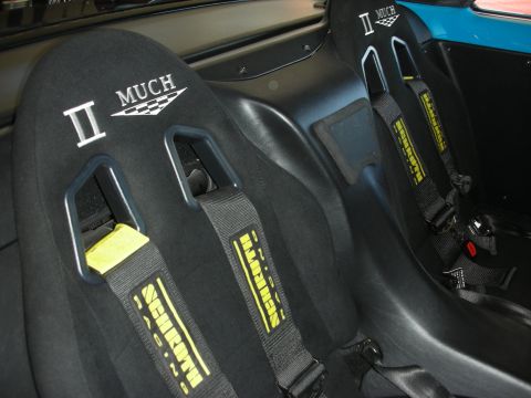 1998 Ford Crown Victoria - Pair of black composite racing bucket seats embroidered II MUCH, fitted with black-and-yellow harness belts.