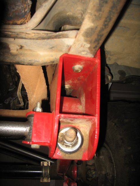 1987 Ford Bronco - Underside view of a vehicle's suspension with a red bracket installed.