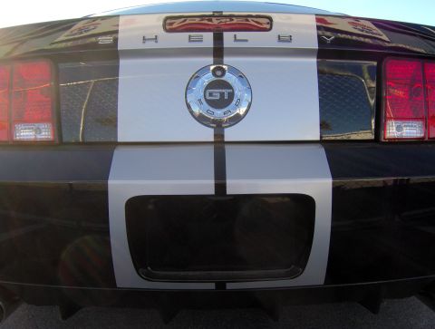 1978 Ford Bronco - Rear view of a black Ford Mustang silver racing stripes and a prominent GT badge.