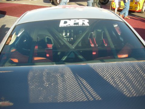 1998 Ford Crown Victoria - Looking through a rear window into a roll-caged interior with red bucket seats, below a DPR SoCal sticker and carbon decklid.
