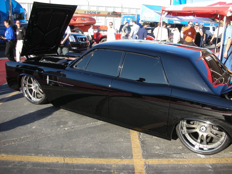 Side profile of a lowered black Lincoln sedan with open hood and chrome wheels