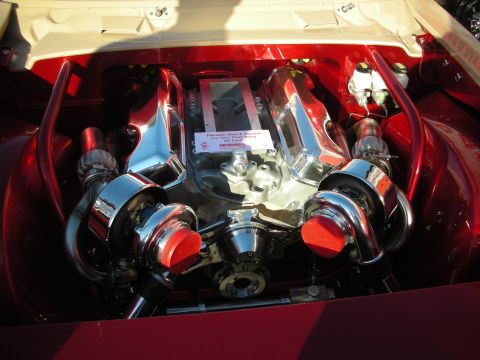 1998 Ford Crown Victoria - Highly polished twin-turbocharged engine fills the bay of a deep-red car, with chrome plumbing and red-capped intakes.