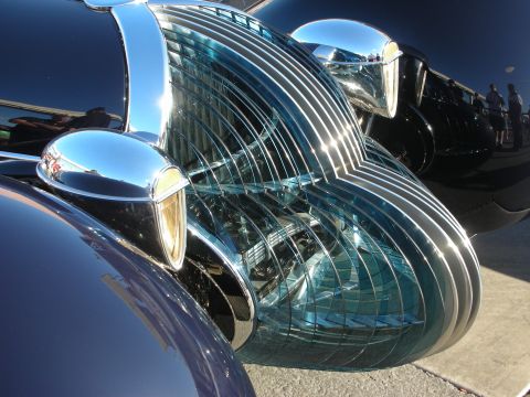 1998 Ford Crown Victoria - Close-up detail of the chrome bullet trim and teal louvered fender panels on a glossy black streamlined custom car.