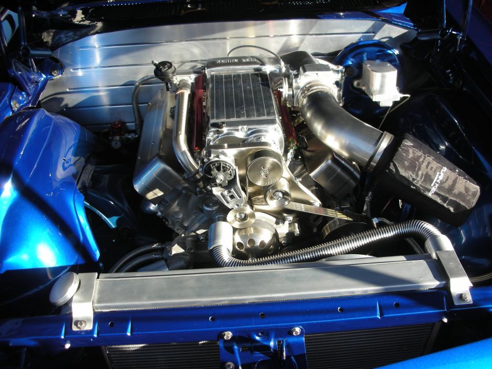 Polished engine with supercharger in blue car engine bay