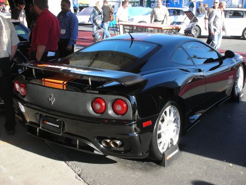 1998 Ford Crown Victoria - Rear three-quarter view of a black Ferrari coupe with a rear wing and quad exhaust as people gather behind it.